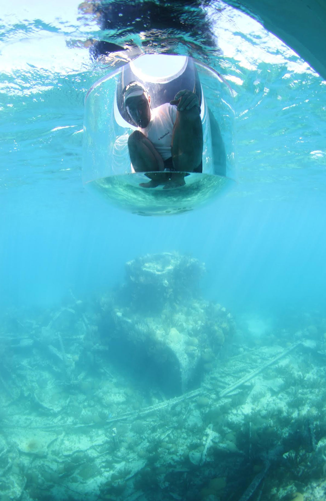 Staying dry while in the water, an explorer hovers over the wreck of the HMS Montana from a wreck-finding drone lowered into the water from a vessel on the surface.
